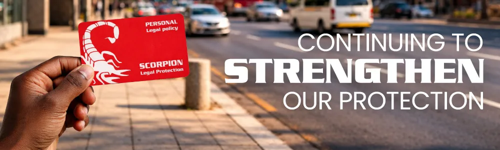 Close-up of a hand holding a red Scorpion Legal Protection membership card labelled 'Personal Legal Policy,' with a blurred city street and traffic in the background. Overlaid text reads 'Continuing to Strengthen Our Protection.'
